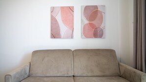 A beige sofa in a room with two abstract paintings on the wall. - Lovely 35 sqm apartment, for four people, located within the renowned Borgo 84 residential complex—which features two swimming pools, a sports area, and a cycle path. The property is just 3 km from the center of Marzamemi, one of Italy's most enchantin (Pachino)
