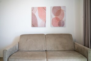 Ein beiges Sofa in einem Raum mit zwei abstrakten Bildern an der Wand.