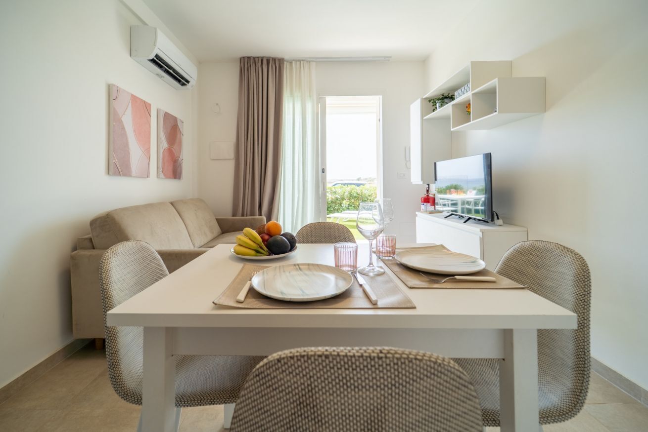 Un salon moderne avec une table à manger pour deux personnes, un canapé et un téléviseur posé sur un meuble.
