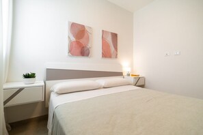 A neatly arranged bedroom with a bed, bedside table, lamp, and abstract wall art. - Lovely 35 sqm apartment, for four people, located within the renowned Borgo 84 residential complex—which features two swimming pools, a sports area, and a cycle path. The property is just 3 km from the center of Marzamemi, one of Italy's most enchantin (Pachino)