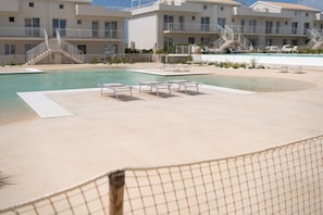 A pool area with lounge chairs, a staircase, and a building with balconies. - Lovely 35 sqm apartment, for four people, located within the renowned Borgo 84 residential complex—which features two swimming pools, a sports area, and a cycle path. The property is just 3 km from the center of Marzamemi, one of Italy's most enchantin (Pachino)