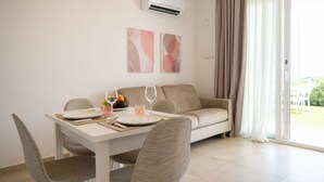 A dining area with a table set for two, a sofa, and a sliding glass door leading to an outdoor area. - Lovely 35 sqm apartment, for four people, located within the renowned Borgo 84 residential complex—which features two swimming pools, a sports area, and a cycle path. The property is just 3 km from the center of Marzamemi, one of Italy's most enchantin (Pachino)