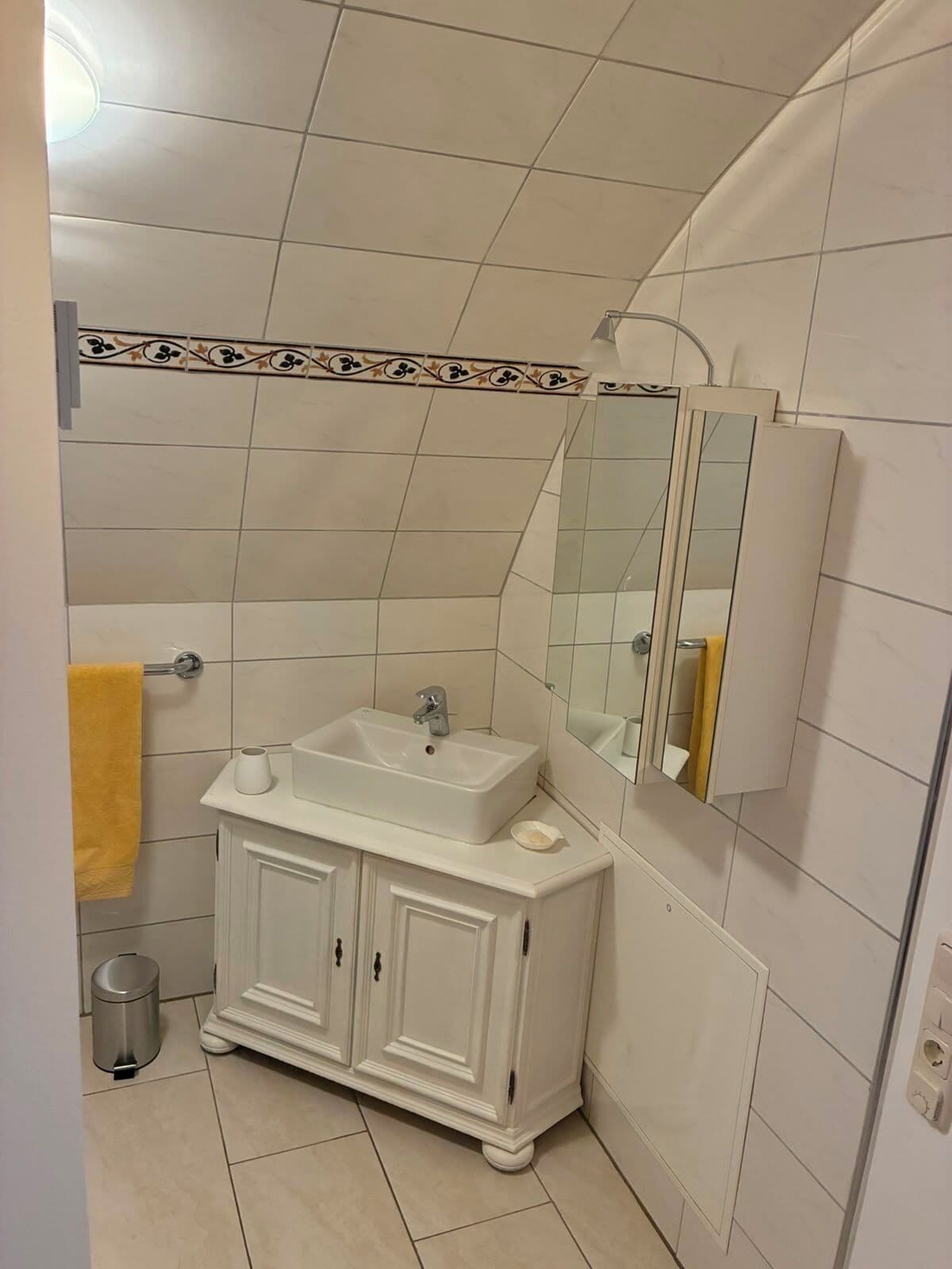 Une salle de bain avec un meuble-lavabo blanc, un miroir et une serviette jaune.