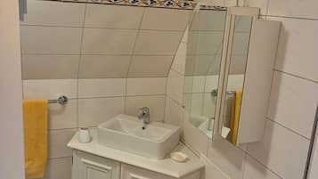 Une salle de bain avec un meuble-lavabo blanc, un miroir et une serviette jaune.