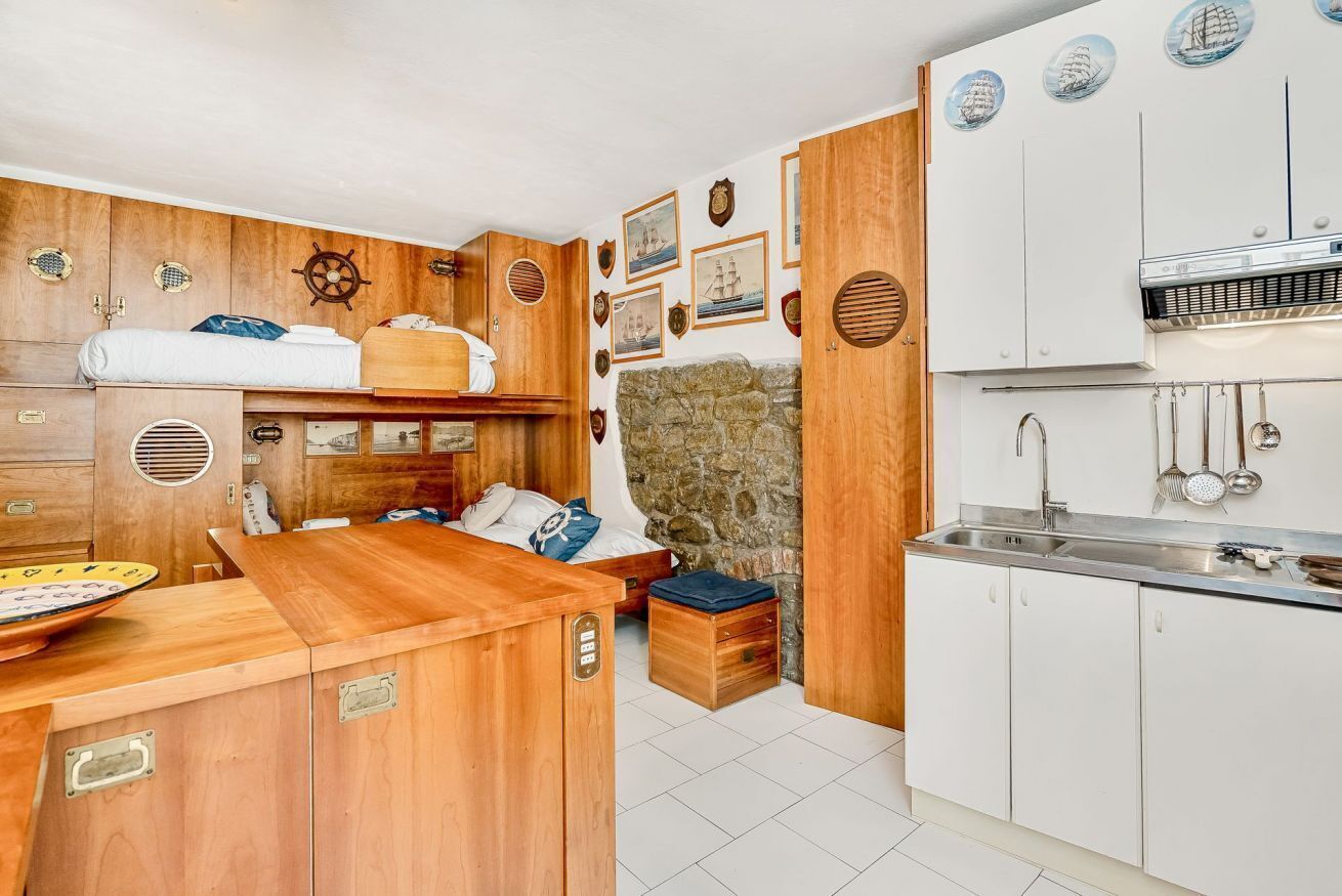 A compact kitchen with wooden cabinetry, a built-in stove, and a small dining area.