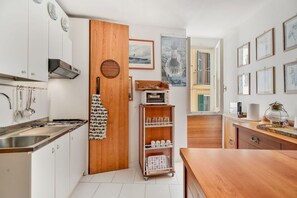 Eine kleine Küche mit weißen Schränken, einer Holztür und einer Kücheninsel.