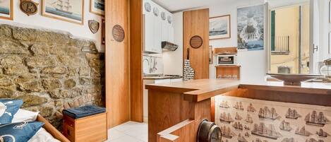 A room with a stone wall, wooden furniture, and maritime-themed decor.