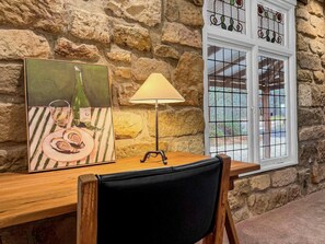 Eine Steinsäule, ein Tisch mit einer Lampe und ein Fenster mit dekorierter Glasscheibe.