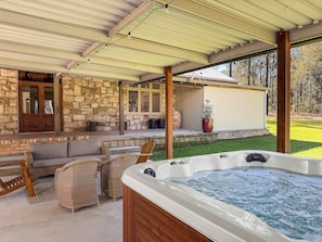 A covered outdoor area with a hot tub, wicker furniture, and a stone wall. - Highwoods Estate - A unique destination in the heart of Wine Country (Pokolbin)