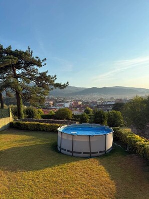 Una piscina en un patio trasero con vistas a un paisaje urbano y montañas al fondo.