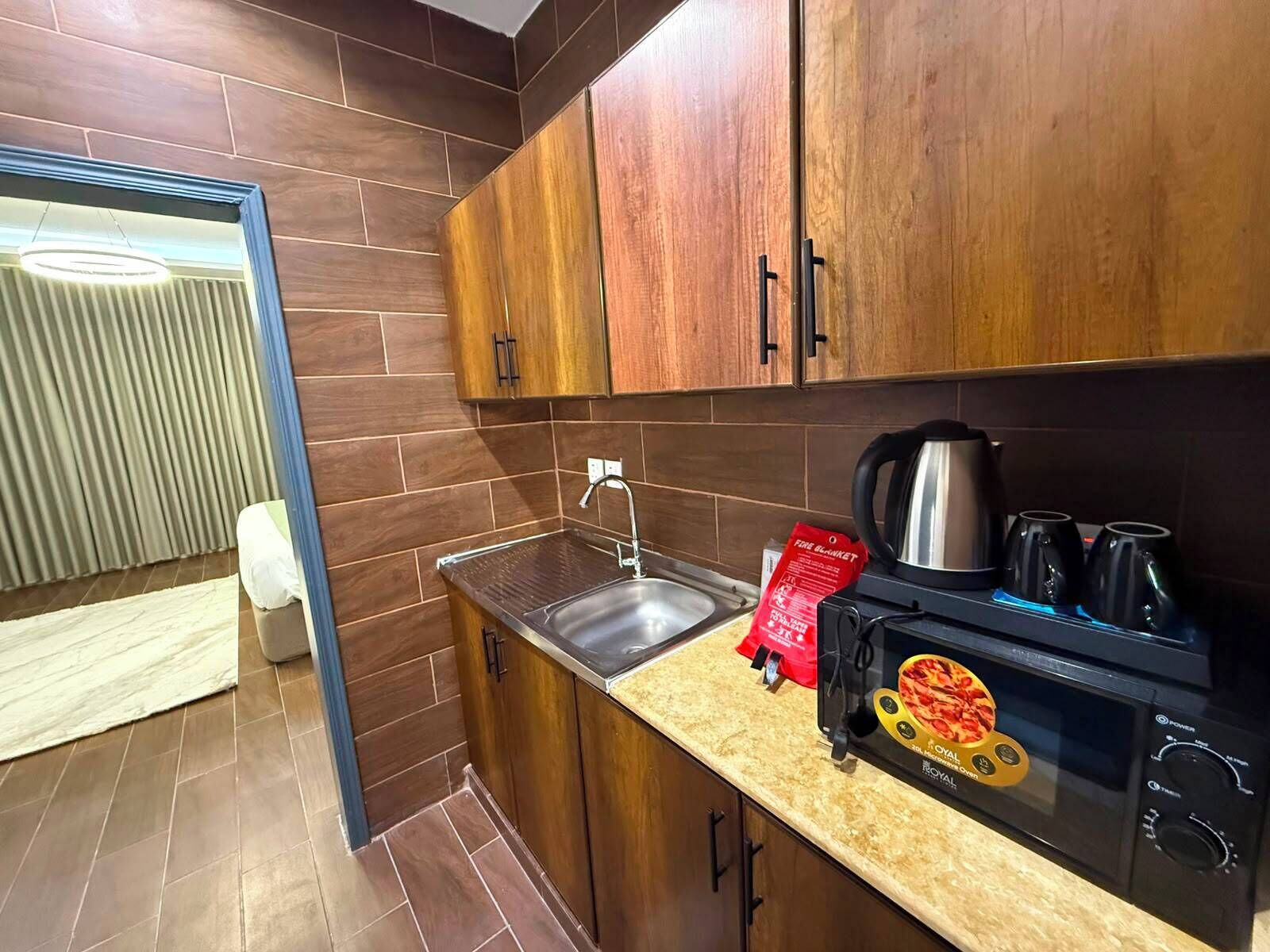 A modern kitchen with wooden cabinets, a stainless steel sink, a black coffee maker, and a branded oven.