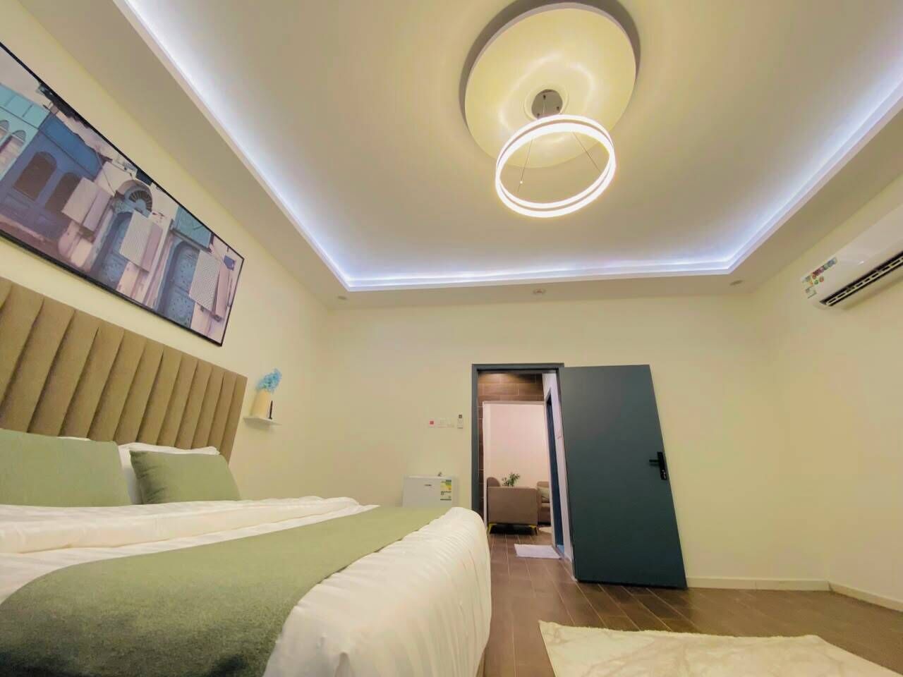 Una habitación de hotel con una cama, una lámpara en el techo y una puerta que da a otra estancia.