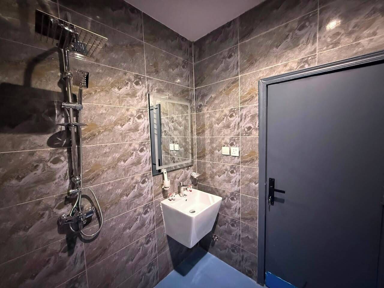 Un baño con ducha, lavamanos y puerta.