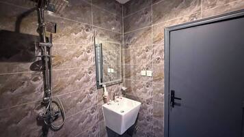 Un baño con ducha, lavamanos y puerta.