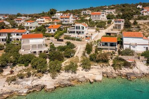 A coastal residential area with houses featuring red-tiled roofs, stone pathways, and clear turquoise waters. - Fantastic 4-bedroom house with AC in Sevid na moru (Sevid na moru)