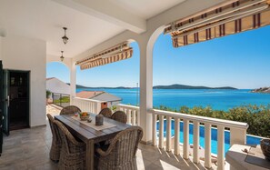 A covered outdoor dining area with wicker furniture, a view of the sea, and a pool. - Fantastic 4-bedroom house with AC in Sevid na moru (Sevid na moru)