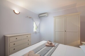 Un dormitorio con cama, cómoda, armario y unidad de aire acondicionado.