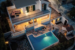 Ein zweistöckiges Haus mit Swimmingpool, Außenbereich und Balkon.