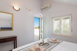 Ein Hotelzimmer mit einem Bett, einem Nachttisch, einem Spiegel, einer Klimaanlage und einem Fenster mit Milchglas.