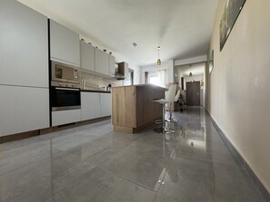 Een moderne keuken met een centraal eiland, roestvrijstalen apparatuur en een strak betegelde vloer.