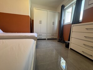 Een slaapkamer met een bed, een kledingkast en een dressoir.