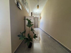Een hal met een bloempot, een houten kast en een hanglamp.