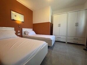 Ein Schlafzimmer mit zwei Betten, einem Kleiderschrank und einer Wandleuchte.