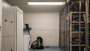 A laundry room with a washing machine, a vacuum cleaner, and metal storage cages. - Alpine Kajo D4 by Aavalevi (Kittilä)