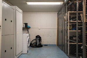 A laundry room with a washing machine, a vacuum cleaner, and metal storage cages. - Alpine Kajo D4 by Aavalevi (Kittilä)