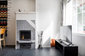A modern living room with a fireplace, a television, and a window. - Alpine Kajo D4 by Aavalevi (Kittilä)