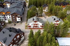 Zona residencial con varias casas de dos pisos, un sendero peatonal central y un bosque denso circundante.