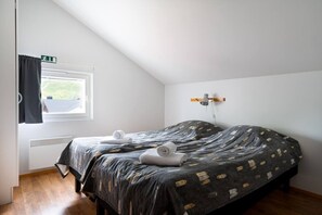 A bedroom with a bed, a window with a view, a wall-mounted lamp, and a towel on the bed. - Alpine Kajo D4 by Aavalevi (Kittilä)