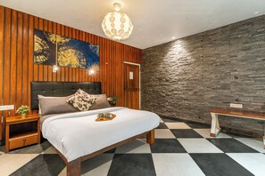 Un dormitorio moderno con pared de paneles de madera, una cama grande con cabecera, un banco y una lámpara colgante.