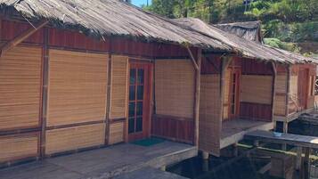 A row of wooden overwater bungalows with thatched roofs, connected by wooden walkways over calm water.