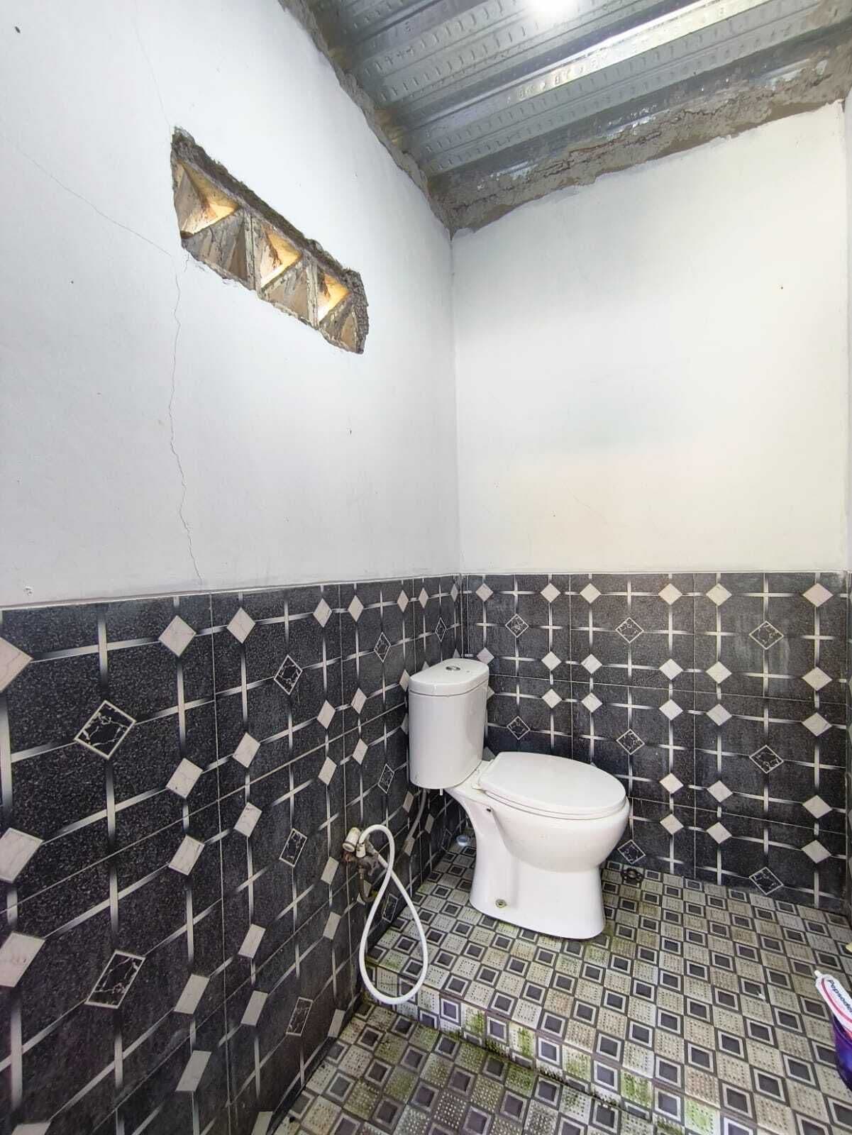 A small bathroom with a toilet, a sink, and tiled walls.