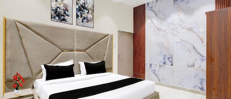 A modern bedroom with a large bed, a nightstand, a wooden wardrobe, and abstract art on the wall.