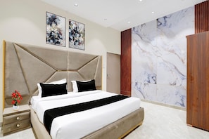 A modern bedroom with a large bed, a nightstand, a wooden wardrobe, and abstract art on the wall. - Collection O City Centre Sapror (Phagwara)