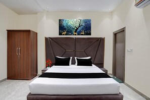 A bedroom with a bed, a wardrobe, a painting, and a door.