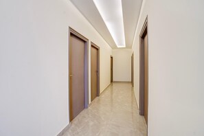 A corridor with doors on both sides, a tiled floor, and a ceiling with recessed lighting.