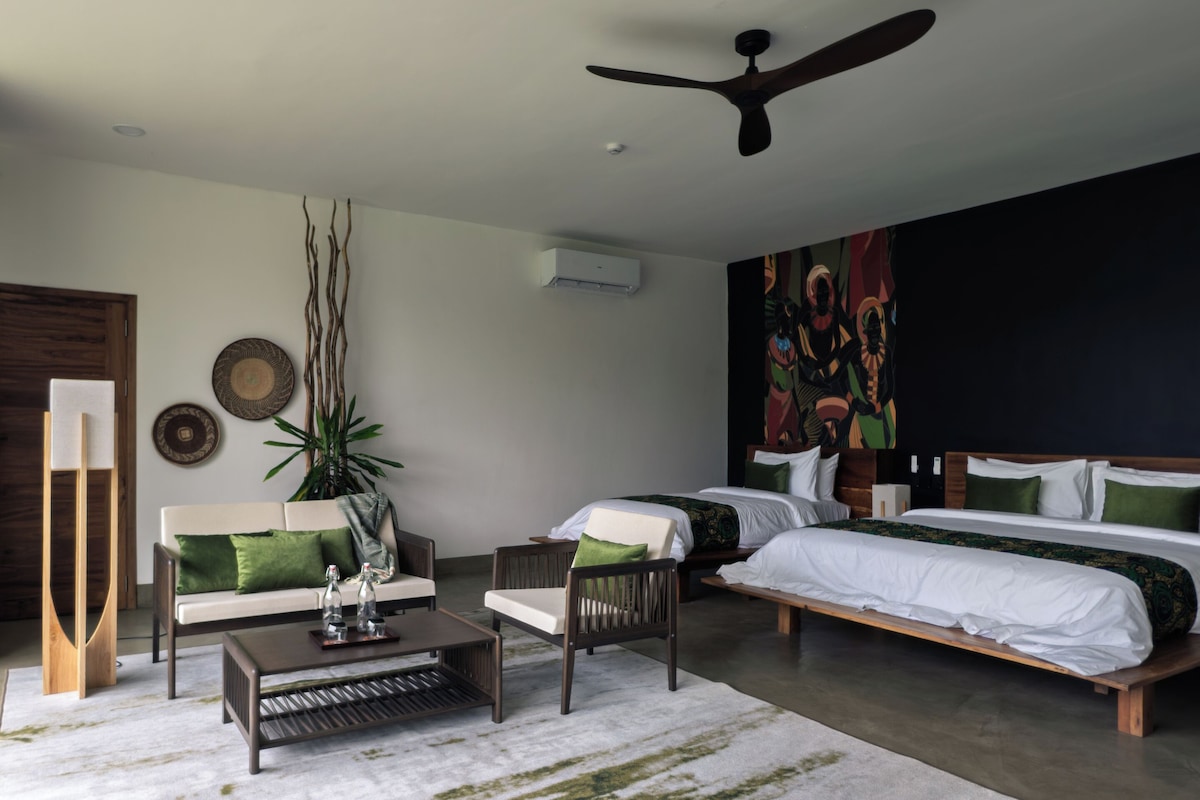 A modern bedroom with a large bed, a sofa, a coffee table, and a ceiling fan.