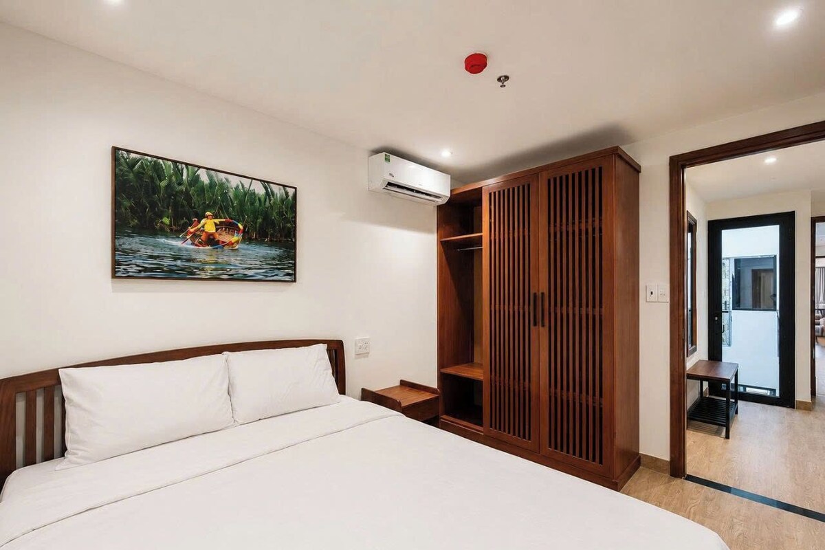 Une chambre à coucher avec un lit, une armoire en bois, un tableau et un appareil de climatisation.