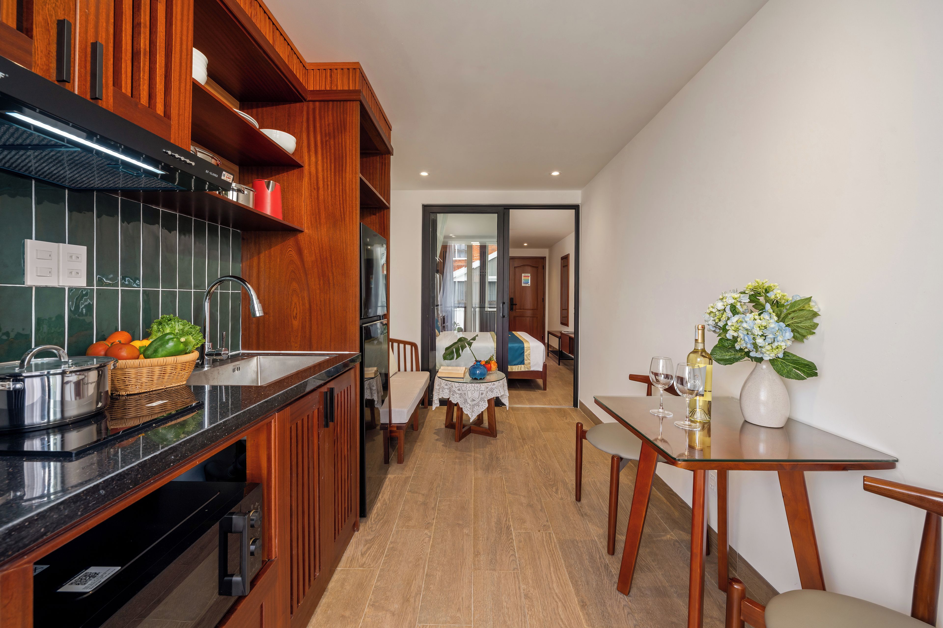 Una cocina moderna con armarios de madera, encimera negra y comedor con mesa y sillas.