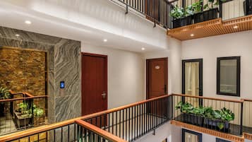 A multi-level interior with a central staircase, wooden railings, and potted plants.