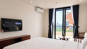 Habitación de hotel con cama, televisor montado en la pared, una mesita pequeña y una silla.