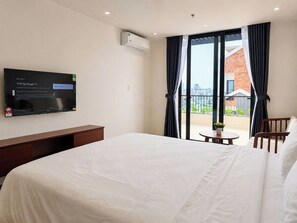 Quarto de hotel com cama, televisão na parede, mesinha e cadeira.