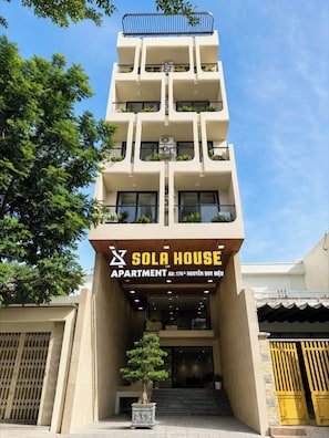 Un immeuble à plusieurs étages sur lequel on peut lire l’inscription « Sola House Apartment ».