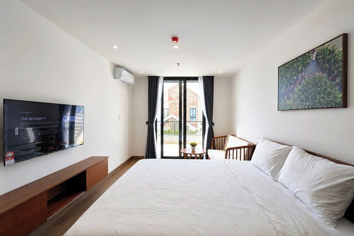 Une chambre d’hôtel avec un lit, une télévision, un bureau et une fenêtre avec des rideaux.