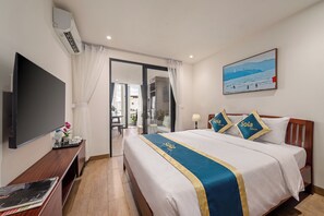 Quarto de hotel com cama, televisão, escrivaninha e um quadro na parede.