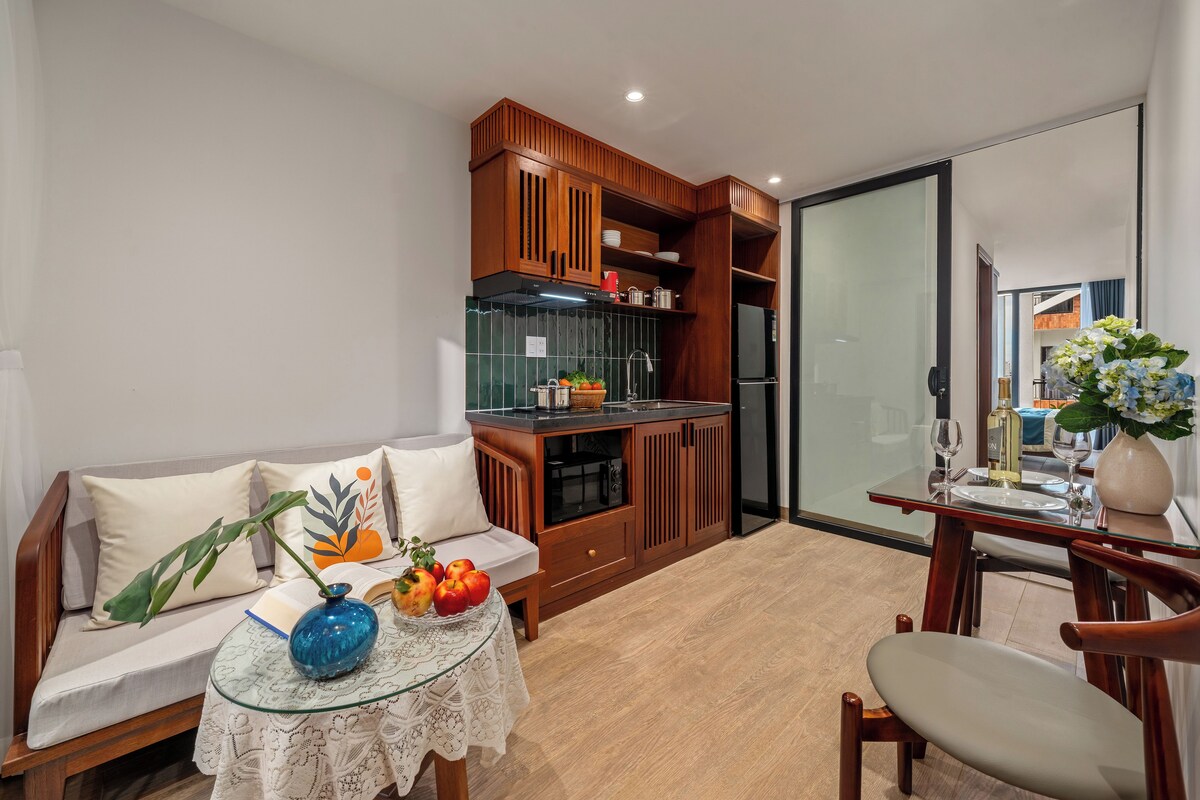 Um espaço compacto com cozinha compacta, área de refeições e sofá com almofadas decorativas.