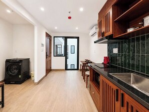 Una cocina con lavadora, un comedor con sillas y vista por una puerta.